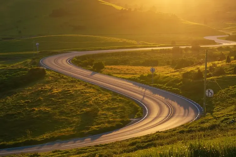A quiet country road winding through hills at sunset